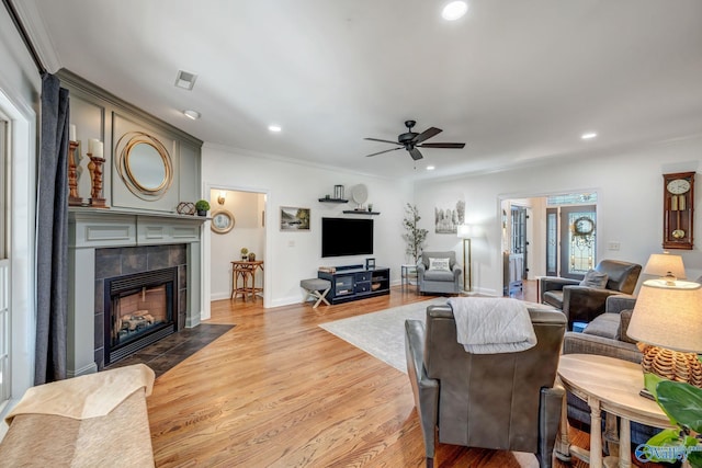 living room with recessed lighting, light wood-style floors, crown molding, ceiling fan, and a tile fireplace