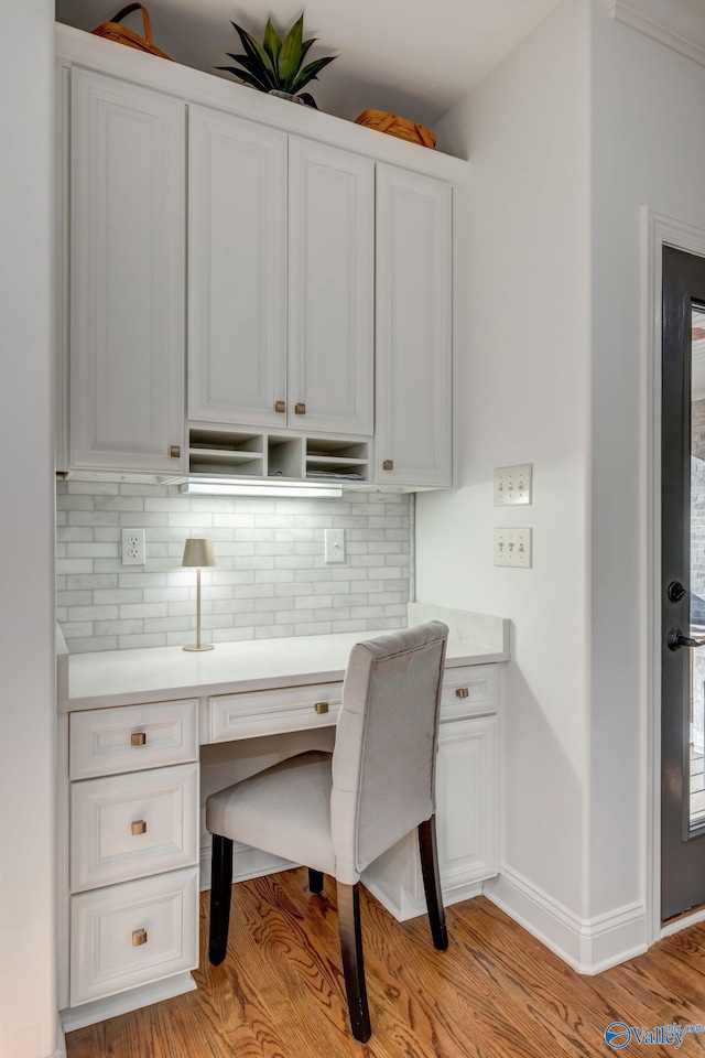 home office with baseboards, light wood finished floors, and built in study area