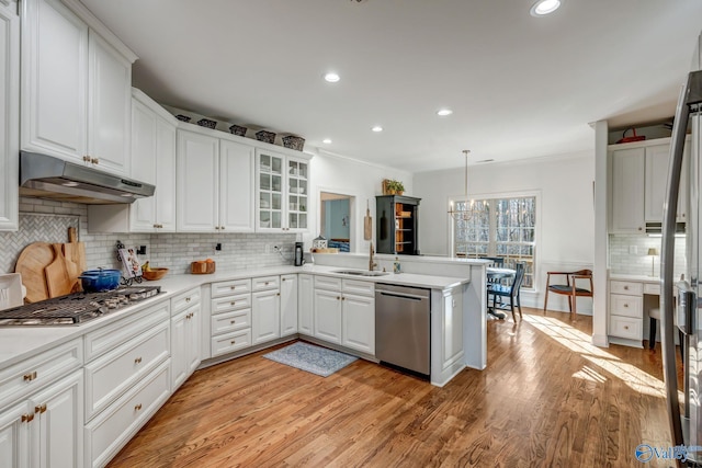 kitchen featuring a peninsula, under cabinet range hood, appliances with stainless steel finishes, white cabinetry, and light wood-type flooring