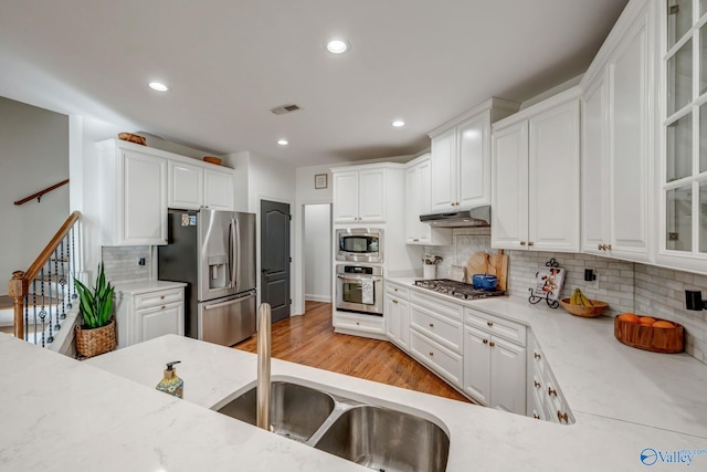 kitchen with under cabinet range hood, visible vents, appliances with stainless steel finishes, and white cabinetry