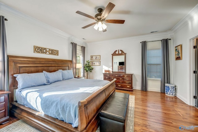 bedroom featuring visible vents, ornamental molding, a ceiling fan, wood finished floors, and baseboards