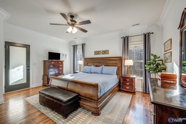 bedroom featuring visible vents, ornamental molding, a ceiling fan, wood finished floors, and baseboards