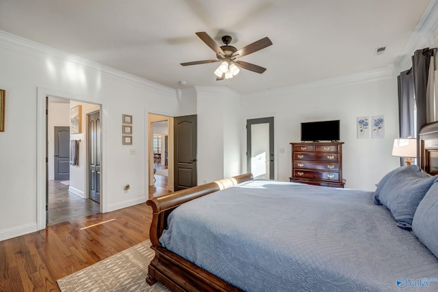 bedroom featuring visible vents, baseboards, wood finished floors, and crown molding