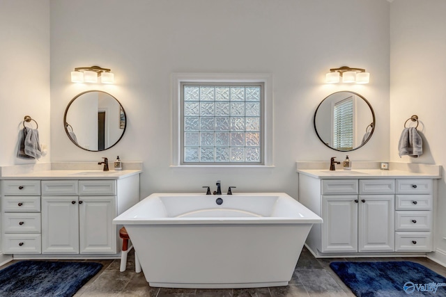 full bathroom featuring a freestanding tub, two vanities, and a sink