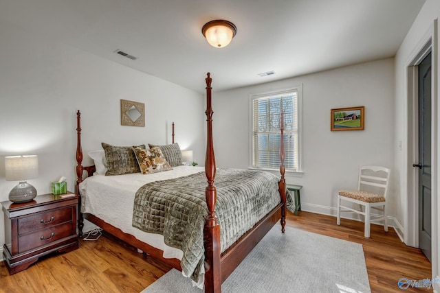 bedroom featuring visible vents, baseboards, and wood finished floors