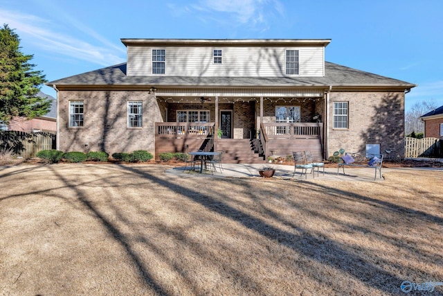 view of front of property with brick siding, a ceiling fan, a patio, and fence