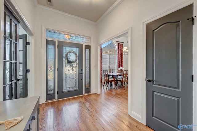 entrance foyer with visible vents, light wood-style floors, crown molding, baseboards, and a chandelier