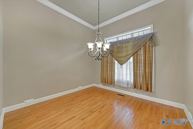 spare room featuring hardwood / wood-style floors, a notable chandelier, and crown molding