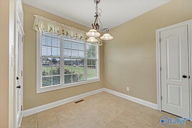 tiled empty room with a notable chandelier