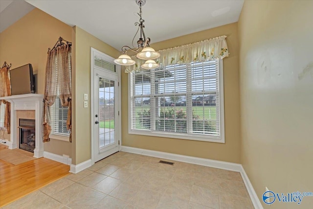 17902 Watercress Dr, Athens, AL 35611 - unfurnished dining area with a chandelier, baseboards, a fireplace, and light tile patterned floors