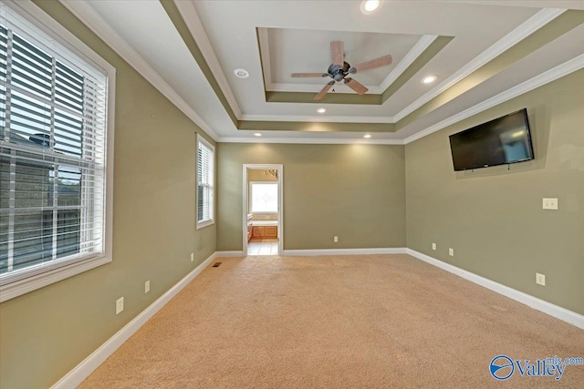 carpeted spare room featuring ceiling fan, a tray ceiling, and ornamental molding