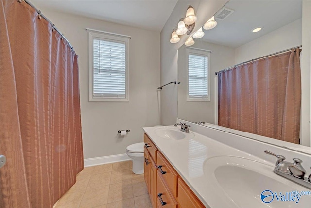 bathroom with tile patterned flooring, a wealth of natural light, vanity, and toilet