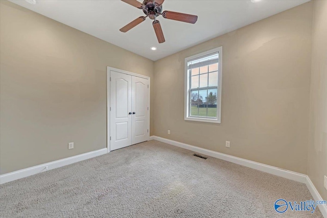 unfurnished bedroom with a closet, carpet flooring, and ceiling fan