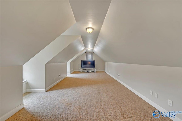 additional living space featuring light colored carpet and lofted ceiling