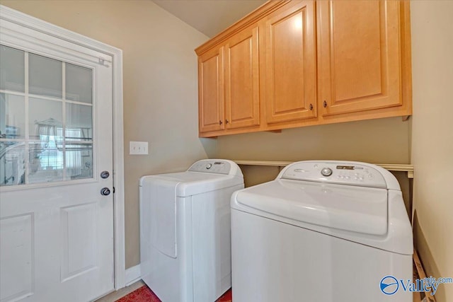 clothes washing area with cabinets and washer and clothes dryer