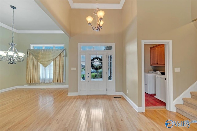 foyer entrance with light hardwood / wood-style floors, a chandelier, crown molding, and independent washer and dryer