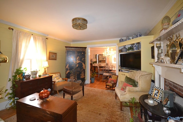 living room with ornamental molding, a chandelier, a fireplace, and light hardwood / wood-style floors