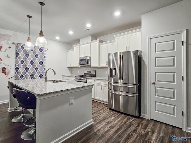 kitchen featuring light stone counters, hanging light fixtures, stainless steel appliances, white cabinetry, and a sink