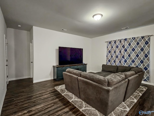 living area with dark wood-type flooring, visible vents, and baseboards