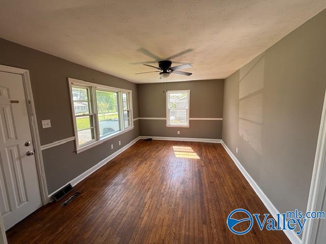 spare room featuring wood finished floors, ceiling fan, baseboards, and visible vents