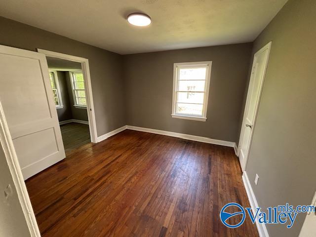 unfurnished bedroom featuring dark wood-style flooring and baseboards