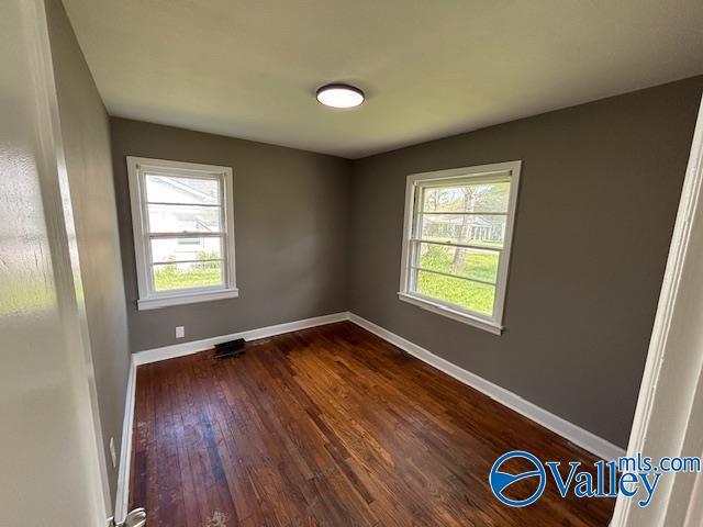 empty room featuring baseboards and dark wood finished floors