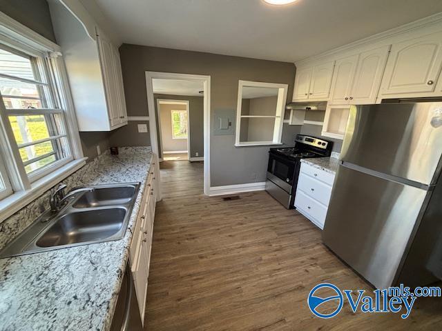 kitchen featuring dark wood-style flooring, baseboards, white cabinets, appliances with stainless steel finishes, and a sink