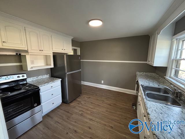 kitchen featuring white cabinetry, dark wood-style flooring, a sink, stainless steel appliances, and baseboards