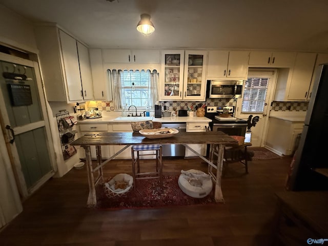 kitchen featuring stainless steel appliances, dark wood-style flooring, a sink, white cabinetry, and light countertops