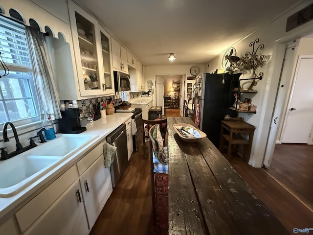 kitchen with glass insert cabinets, stainless steel appliances, light countertops, white cabinetry, and a sink