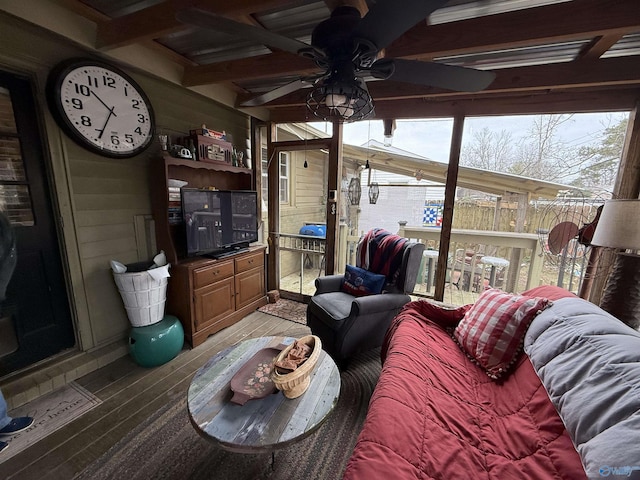 living room featuring ceiling fan, wood walls, plenty of natural light, and light wood-style floors