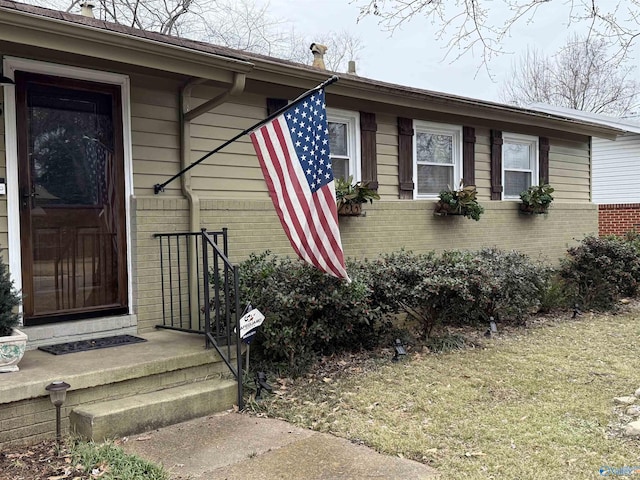 property entrance featuring a lawn and brick siding