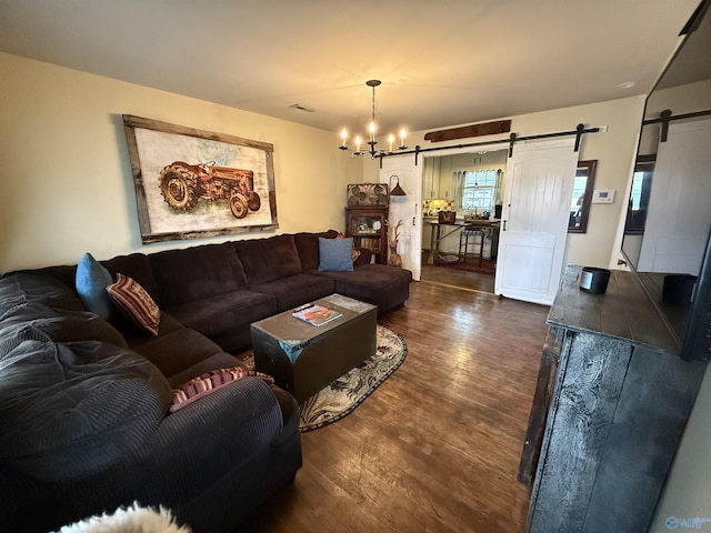 living room featuring visible vents, dark wood finished floors, an inviting chandelier, and a barn door