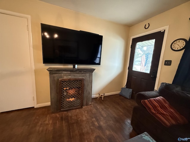 living room with a warm lit fireplace, baseboards, and dark wood finished floors