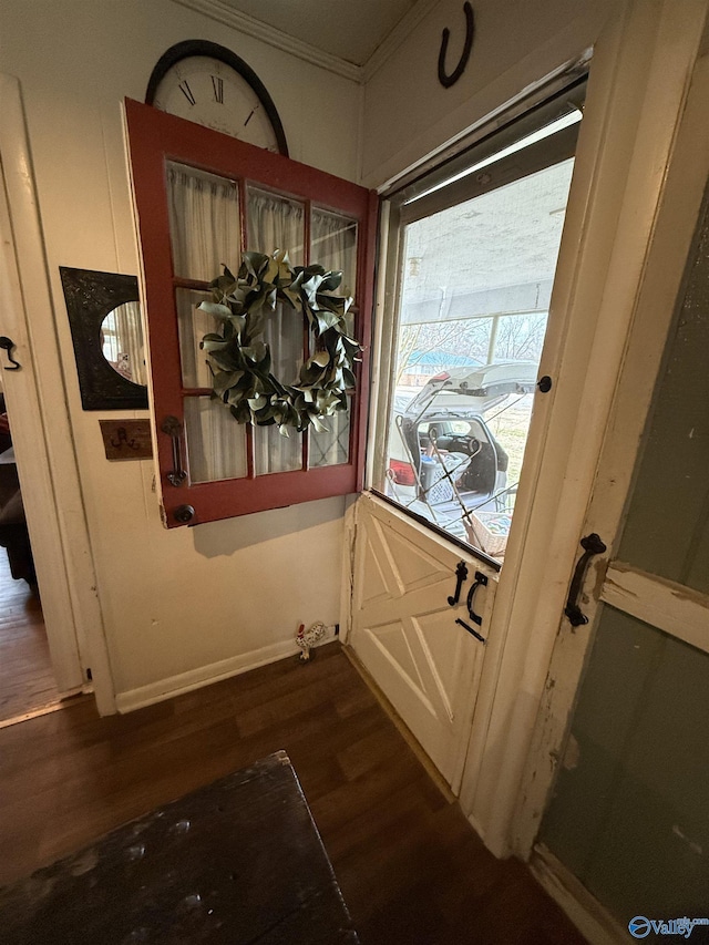 doorway to outside with ornamental molding, dark wood finished floors, and baseboards