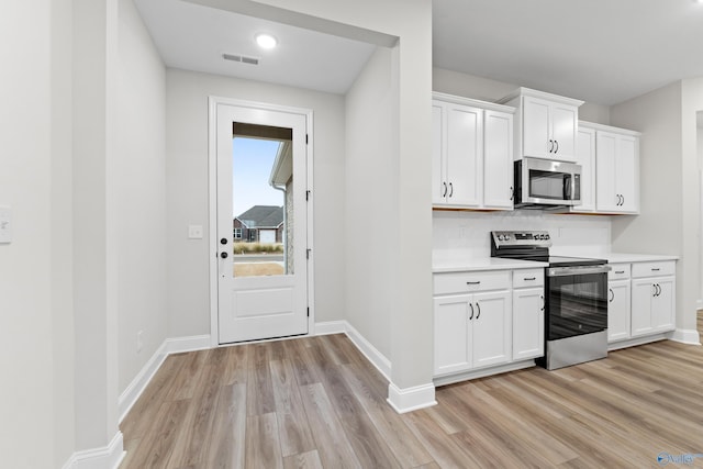 kitchen featuring light wood finished floors, appliances with stainless steel finishes, light countertops, and baseboards