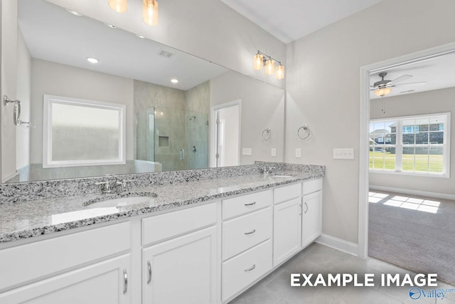 bathroom with double vanity, a stall shower, a ceiling fan, and a sink