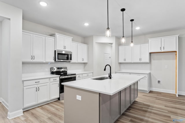 kitchen with light wood-style flooring, an island with sink, a sink, stainless steel appliances, and white cabinets