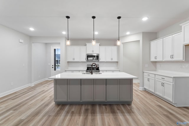 kitchen featuring light countertops, light wood-type flooring, appliances with stainless steel finishes, and a sink