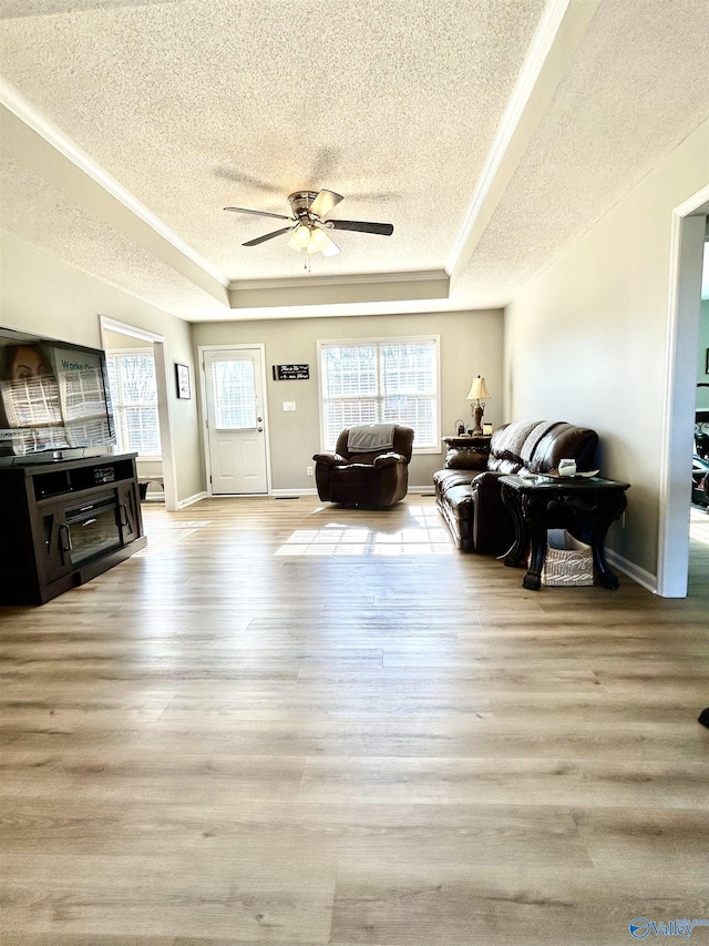 living room with ceiling fan, a raised ceiling, light hardwood / wood-style flooring, and a textured ceiling