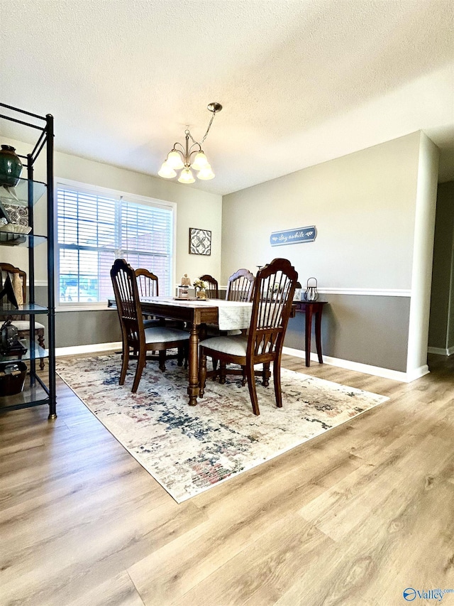 dining area featuring wood-type flooring, a notable chandelier, and a textured ceiling