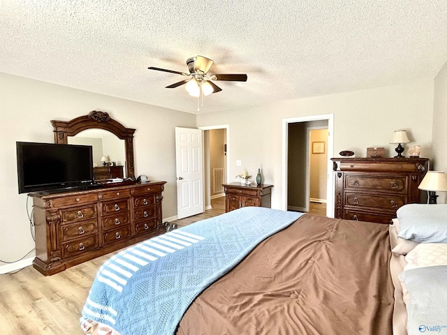 bedroom with a textured ceiling, ceiling fan, and light wood-type flooring