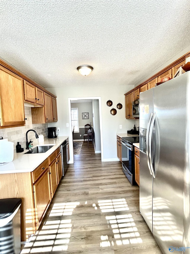 kitchen featuring tasteful backsplash, sink, stainless steel appliances, and light wood-type flooring