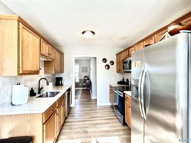 kitchen with sink, backsplash, stainless steel appliances, and light wood-type flooring