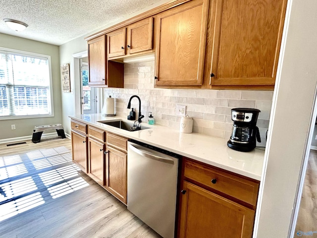 kitchen featuring dishwasher, sink, decorative backsplash, light hardwood / wood-style floors, and a textured ceiling