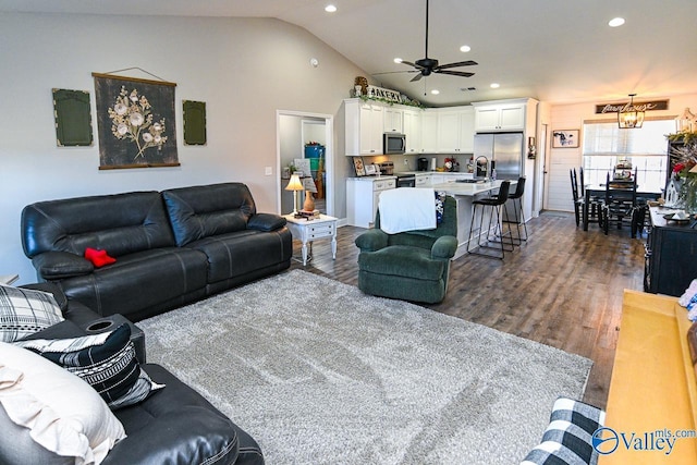 living room with ceiling fan with notable chandelier, lofted ceiling, dark hardwood / wood-style flooring, and sink