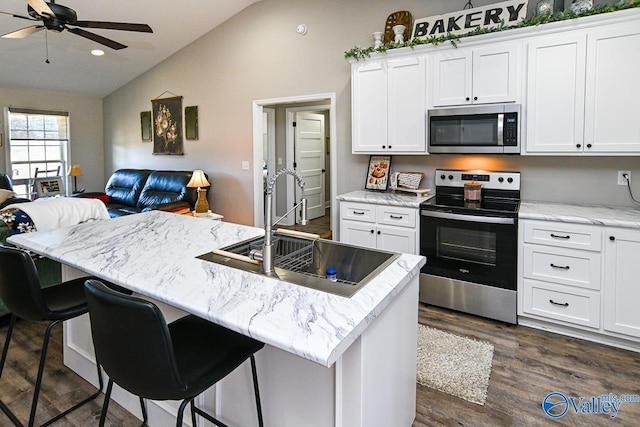 kitchen featuring white cabinetry, stainless steel appliances, sink, and an island with sink