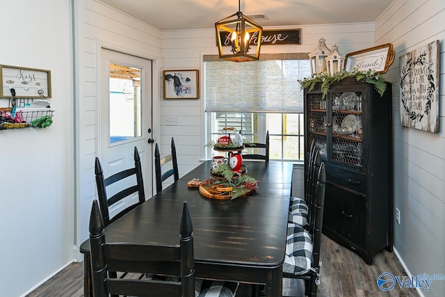 dining room featuring wooden walls, dark hardwood / wood-style flooring, and a notable chandelier