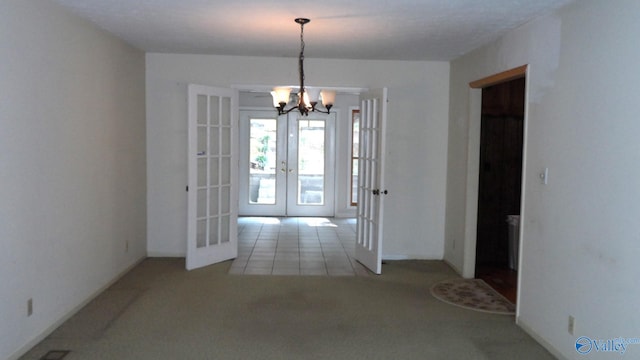 spare room with french doors, light colored carpet, and an inviting chandelier