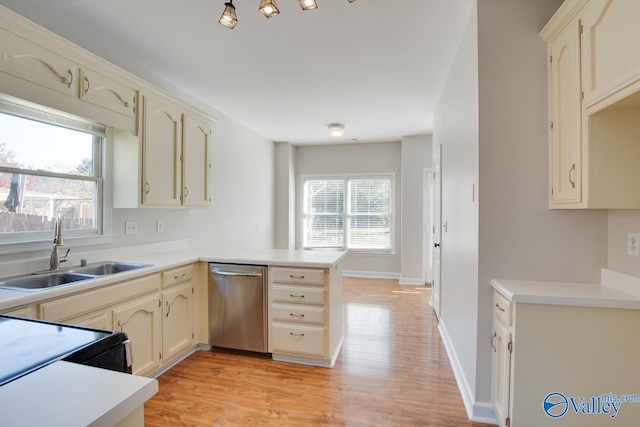 kitchen featuring dishwasher, light wood-type flooring, sink, and a healthy amount of sunlight